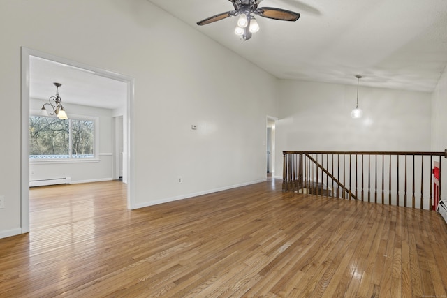 empty room with lofted ceiling, ceiling fan with notable chandelier, light hardwood / wood-style flooring, and a baseboard radiator