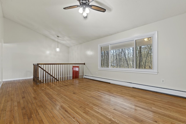 unfurnished room featuring baseboard heating, lofted ceiling, hardwood / wood-style floors, and ceiling fan