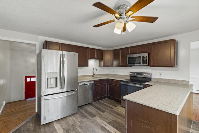 kitchen with stainless steel appliances, sink, dark hardwood / wood-style floors, kitchen peninsula, and dark brown cabinets