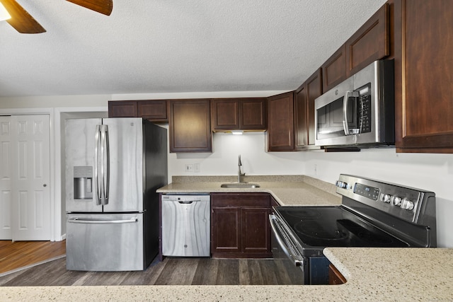 kitchen featuring a textured ceiling, stainless steel appliances, sink, dark hardwood / wood-style floors, and dark brown cabinets