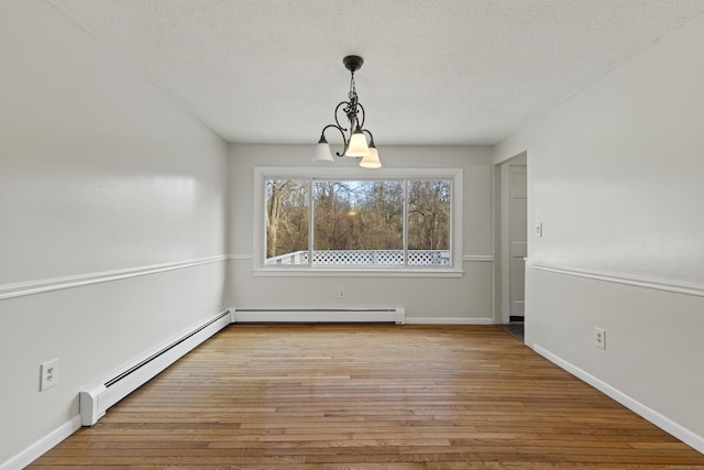 unfurnished dining area with a textured ceiling, baseboard heating, light hardwood / wood-style flooring, and an inviting chandelier