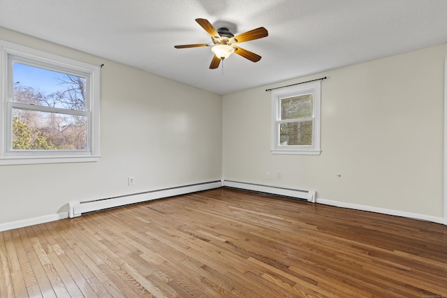 empty room with light hardwood / wood-style flooring, plenty of natural light, and a baseboard radiator