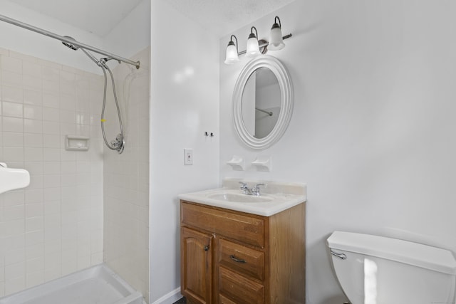 bathroom featuring toilet, vanity, tiled shower, and a textured ceiling