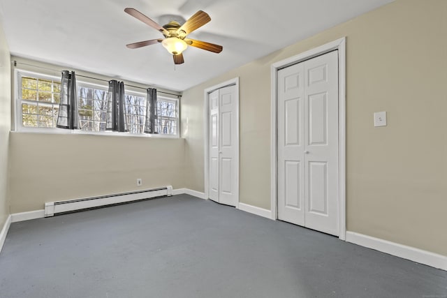 unfurnished bedroom featuring a baseboard heating unit, ceiling fan, and two closets