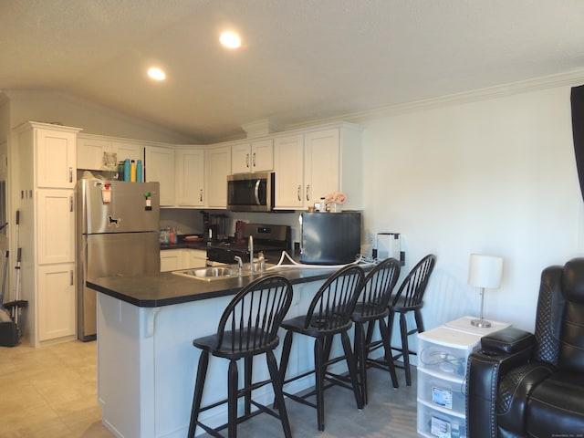 kitchen with sink, vaulted ceiling, a breakfast bar area, white cabinets, and appliances with stainless steel finishes