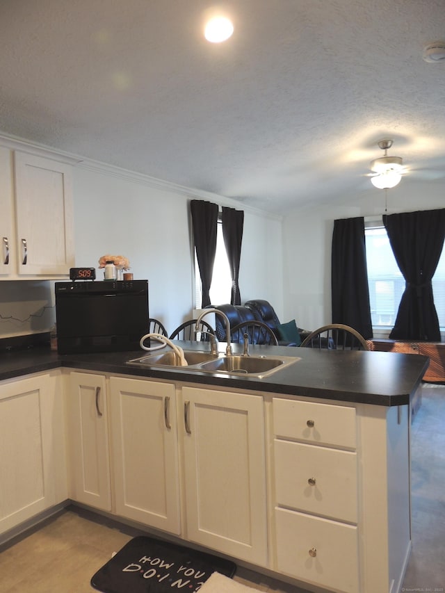 kitchen with white cabinetry, sink, kitchen peninsula, a textured ceiling, and ornamental molding