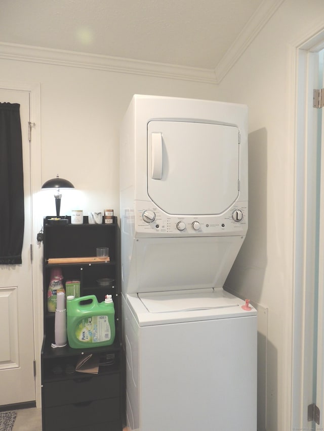 washroom featuring crown molding and stacked washer and clothes dryer