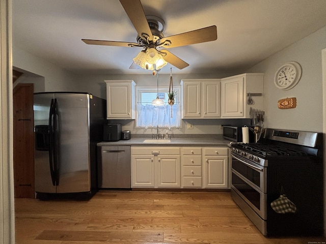 kitchen featuring stainless steel appliances, sink, light hardwood / wood-style flooring, and white cabinets