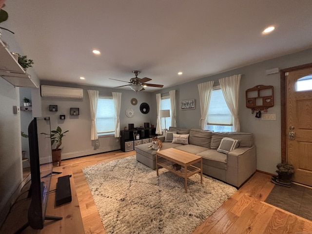 living room with a baseboard radiator, a wall mounted air conditioner, ceiling fan, and light hardwood / wood-style floors