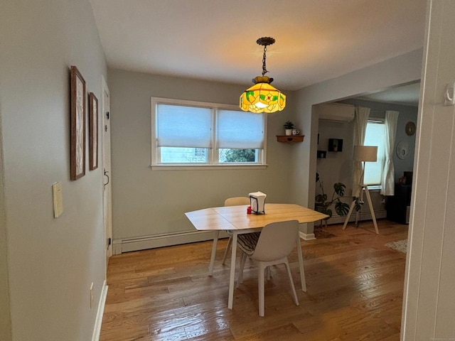 dining room with hardwood / wood-style flooring, a baseboard heating unit, and a wealth of natural light