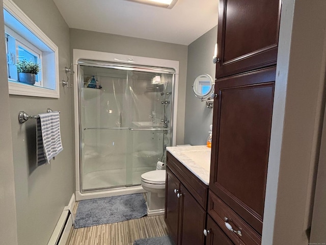 bathroom featuring baseboard heating, vanity, toilet, and a shower with shower door