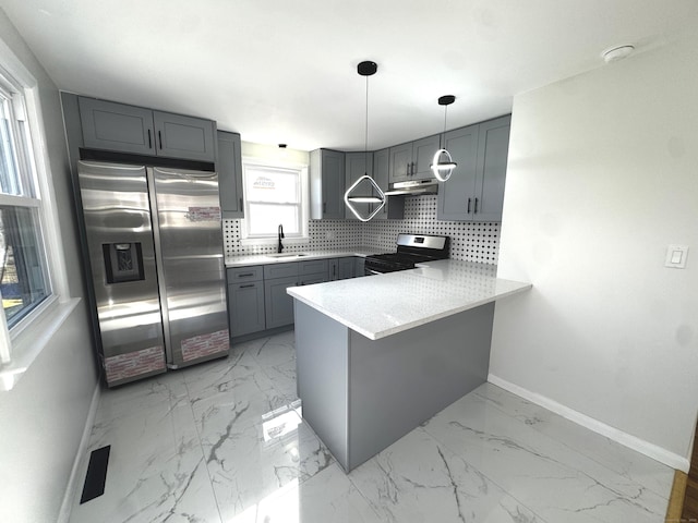 kitchen featuring stainless steel appliances, sink, kitchen peninsula, gray cabinets, and pendant lighting