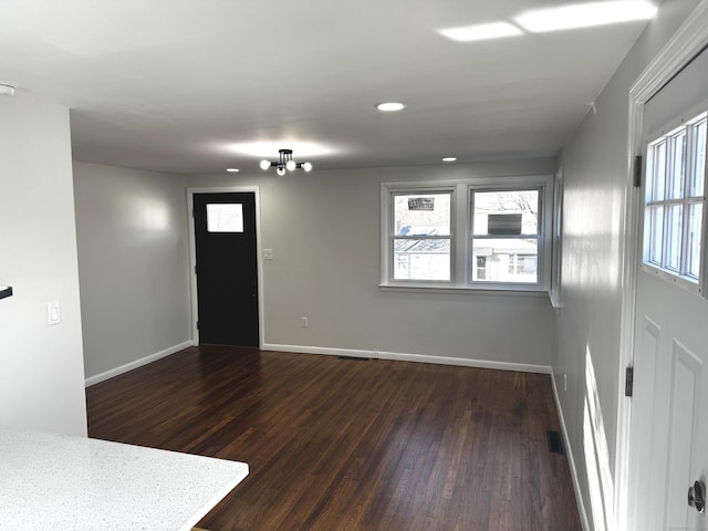 foyer entrance with an inviting chandelier and dark hardwood / wood-style floors