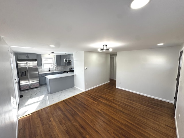 kitchen featuring an inviting chandelier, tasteful backsplash, stove, stainless steel refrigerator with ice dispenser, and gray cabinetry