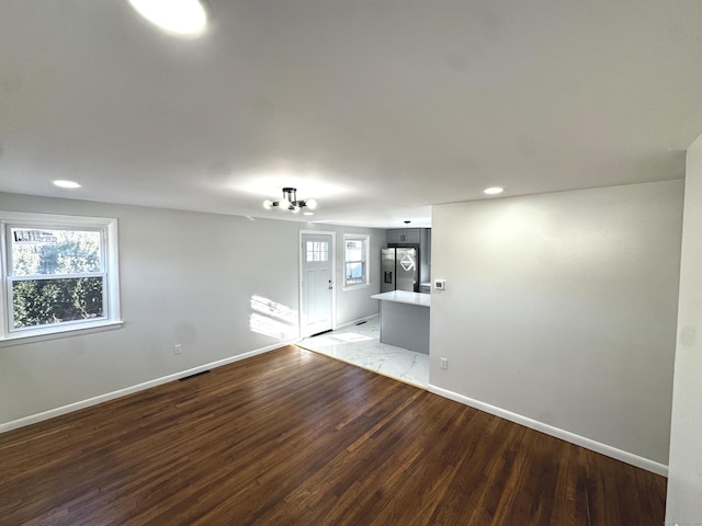 empty room with wood-type flooring and a notable chandelier