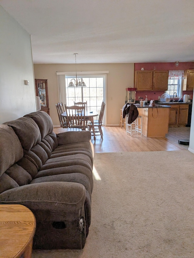 carpeted living room featuring a chandelier, plenty of natural light, and sink