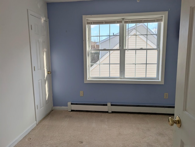 unfurnished room featuring baseboard heating and light carpet