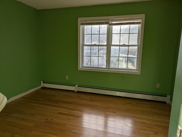 unfurnished room featuring baseboard heating and light wood-type flooring