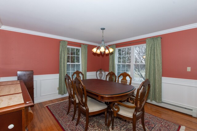 dining room featuring a notable chandelier, crown molding, a baseboard radiator, and hardwood / wood-style floors