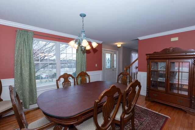 dining area featuring crown molding, wood-type flooring, and an inviting chandelier