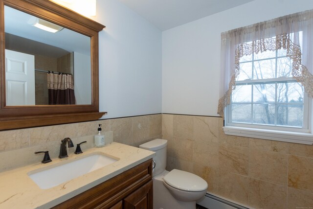 bathroom with vanity, tile walls, a wealth of natural light, and a baseboard radiator