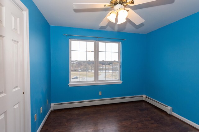 spare room with ceiling fan, a baseboard heating unit, and dark hardwood / wood-style flooring