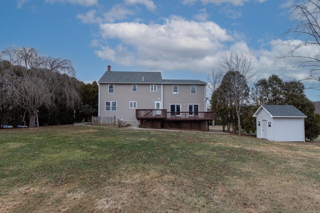 back of property featuring a storage shed, a yard, and a wooden deck