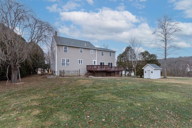 back of house featuring a wooden deck, an outbuilding, and a yard