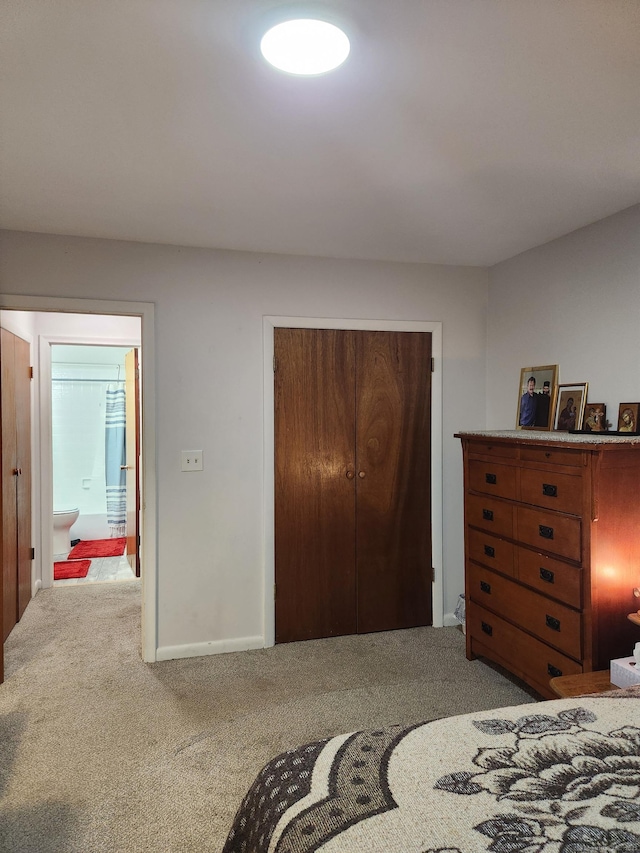 bedroom with a closet, carpet flooring, and ensuite bath