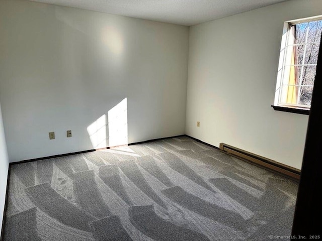 carpeted spare room with baseboard heating and a healthy amount of sunlight