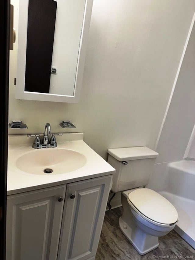 bathroom with toilet, wood-type flooring, and vanity