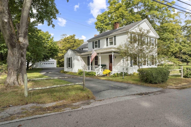 view of front of house featuring a porch, a front lawn, a garage, and an outbuilding