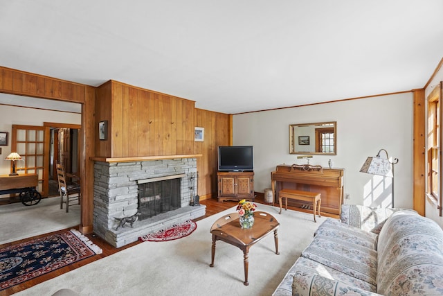 living room featuring wooden walls, crown molding, and a stone fireplace