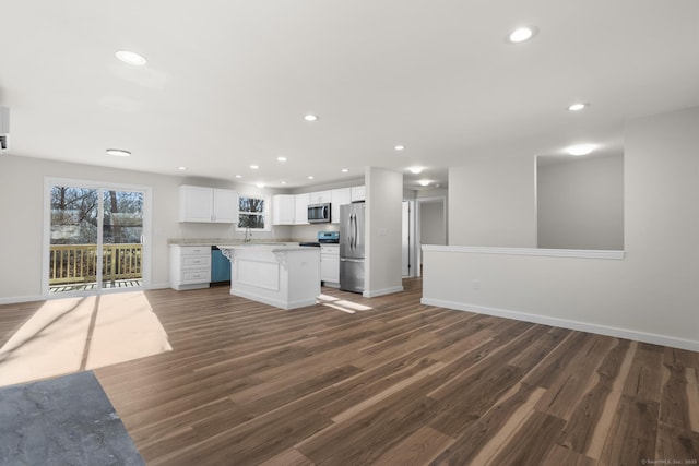 kitchen with appliances with stainless steel finishes, a center island, dark hardwood / wood-style flooring, white cabinets, and sink