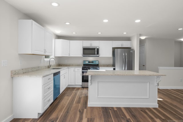 kitchen with a kitchen island, stainless steel appliances, white cabinets, and sink