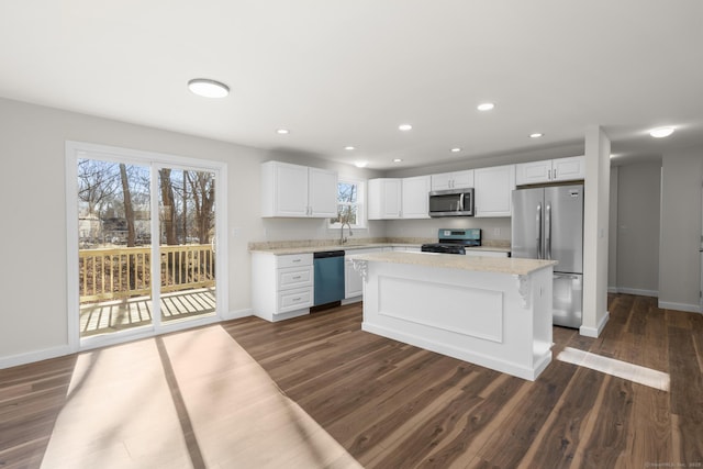 kitchen featuring stainless steel appliances, white cabinetry, light stone countertops, a kitchen island, and dark hardwood / wood-style flooring