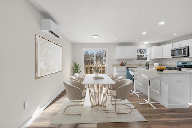 dining space with sink, a wall unit AC, and hardwood / wood-style flooring