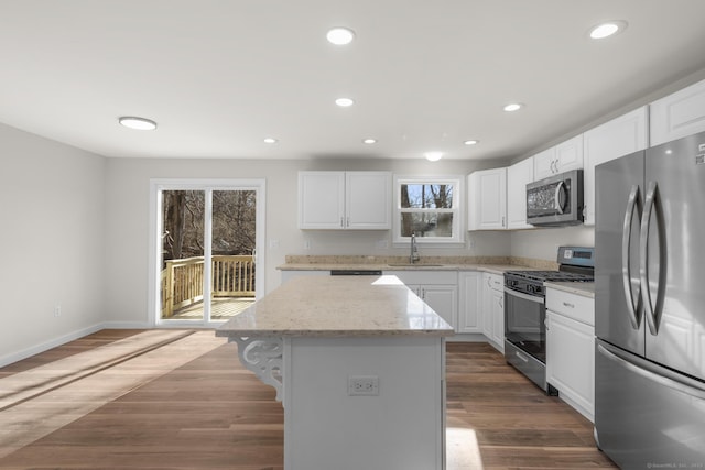 kitchen featuring stainless steel appliances, white cabinetry, sink, and a center island