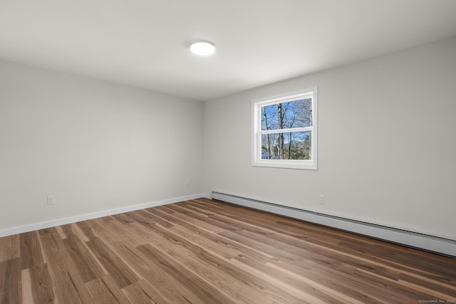 spare room with a baseboard heating unit and hardwood / wood-style flooring