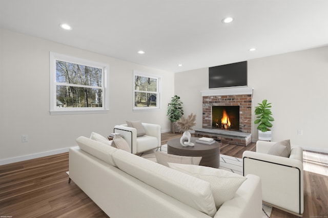 living room with a brick fireplace and hardwood / wood-style flooring