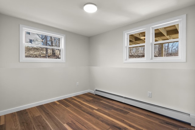 empty room with dark hardwood / wood-style flooring, a baseboard radiator, and a wealth of natural light