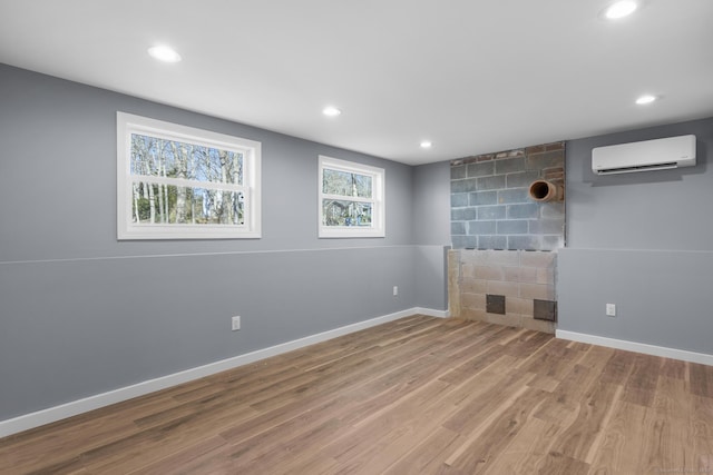 unfurnished living room with a wall mounted air conditioner and wood-type flooring