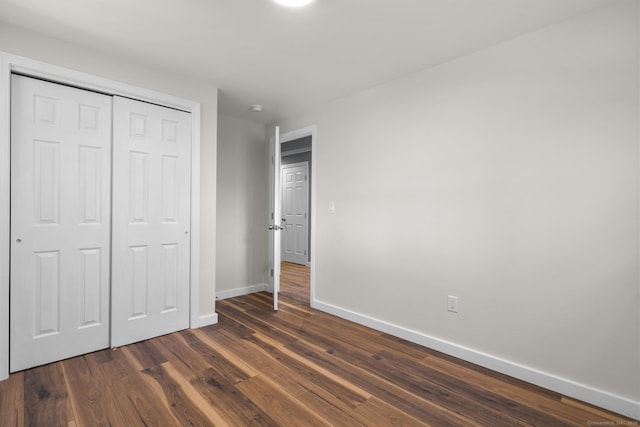 unfurnished bedroom with dark hardwood / wood-style flooring and a closet