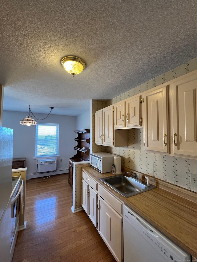 kitchen with hardwood / wood-style floors, pendant lighting, sink, white cabinets, and white appliances