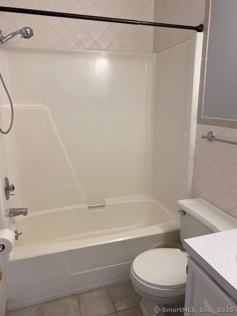 full bathroom featuring vanity, washtub / shower combination, tile patterned flooring, toilet, and tile walls