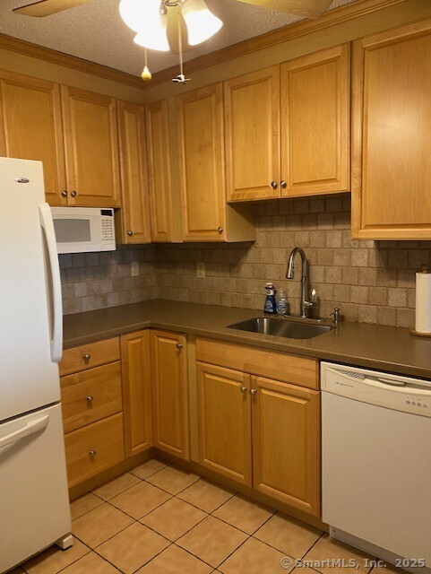 kitchen featuring light tile patterned flooring, white appliances, tasteful backsplash, and sink