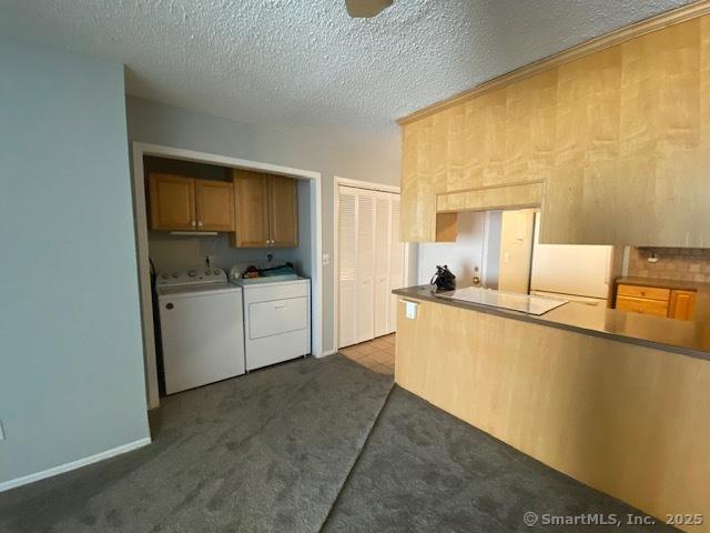 kitchen featuring dark carpet, independent washer and dryer, and a textured ceiling