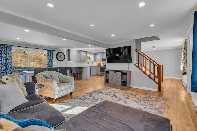 living room featuring light wood-type flooring, crown molding, and sink