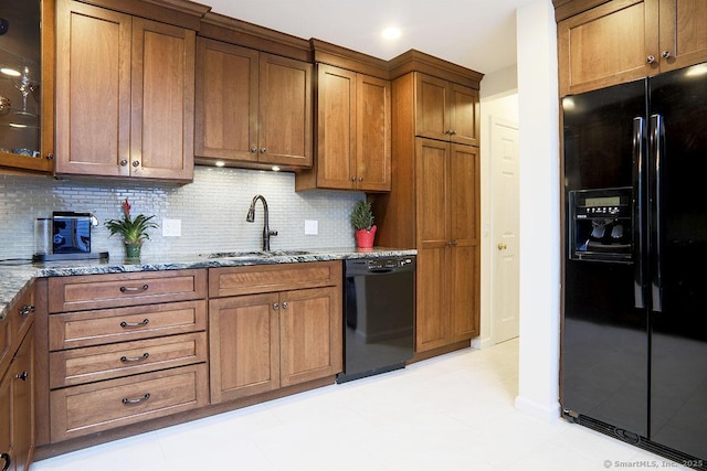 kitchen featuring sink, backsplash, light tile patterned floors, black appliances, and light stone countertops