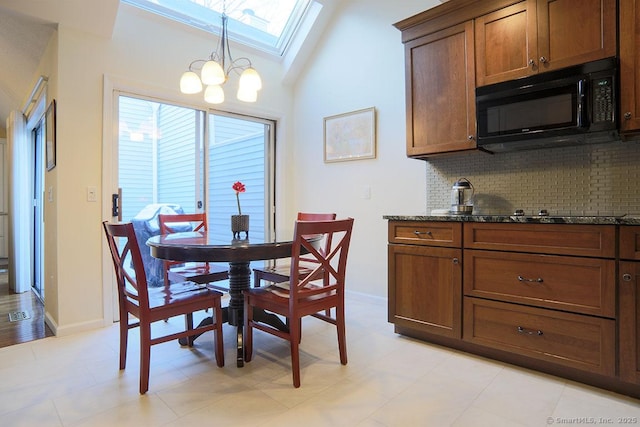 dining area featuring lofted ceiling with skylight and a chandelier